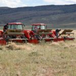 Three tractors with combine-type attachments on front.